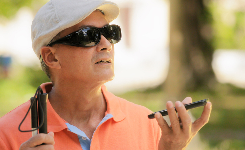 Un hombre mayor con discapacidad visual utiliza un tel&eacute;fono m&oacute;vil