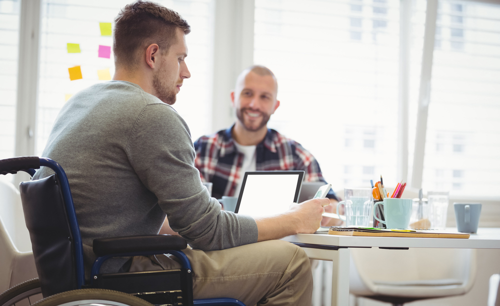 Un joven en silla de ruedas utiliza distinta tecnolog&iacute;a en su puesto de trabajo