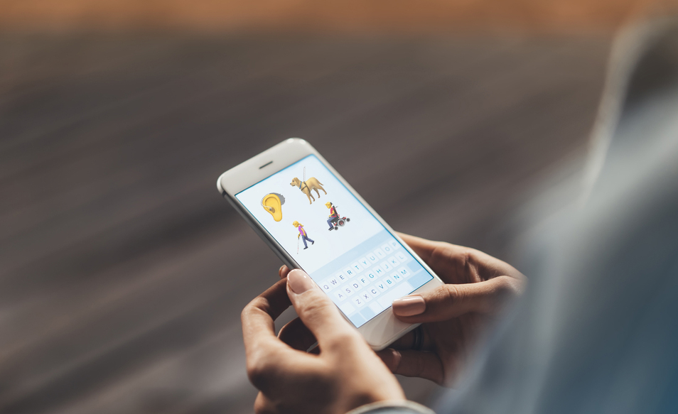 Una personas utiliza un smartphone con los emojis sobre personas con discapacidad en la pantalla
