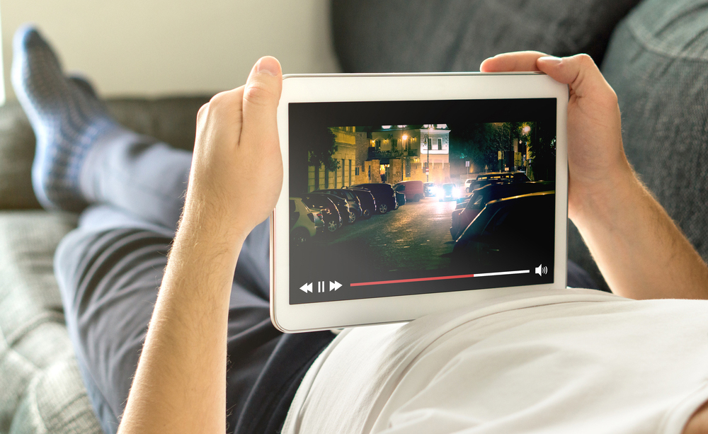 Una persona ve la televisi&oacute;n en una tableta tumbado en un sof&aacute;